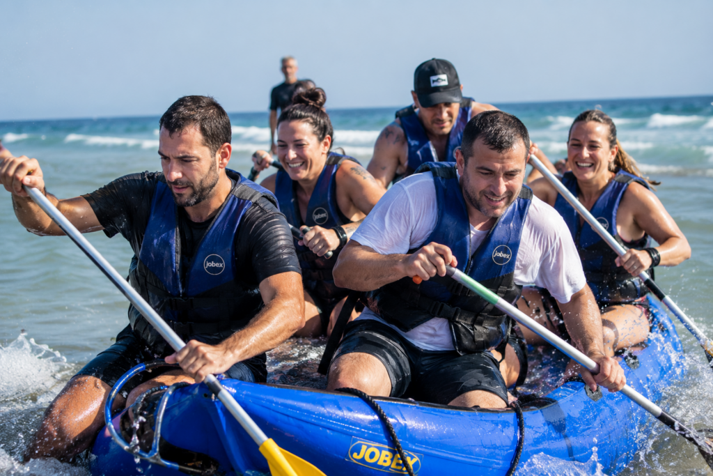 Equipo de empresa en un evento corporativo con valores: esfuerzo real en kayak en la playa de Castelldefels